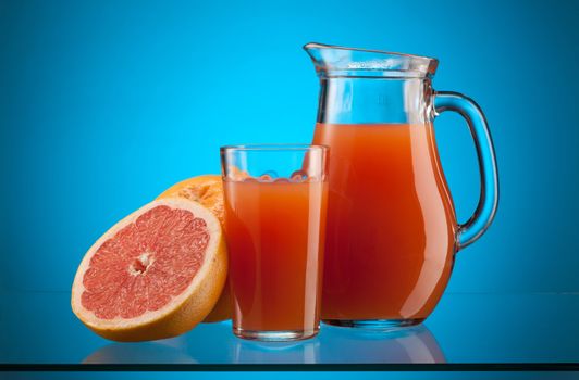 fresh grapefruit juice in the glass and jar over blue