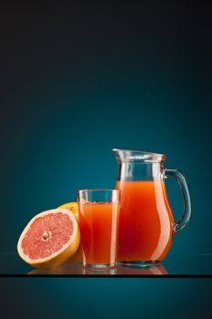 fresh grapefruit juice in the glass and jar over blue