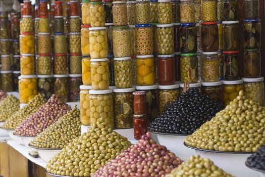 Market stall selling fresh olives and bottled food in the main souk of Marrakesh, Morocco.
