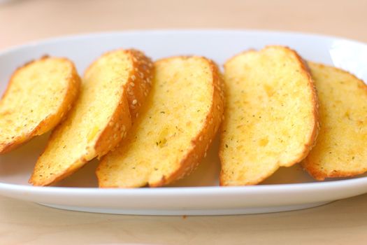Garlic bread with herbs on white bread dish.