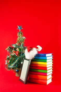 Electronic book reader with stack of books against red background