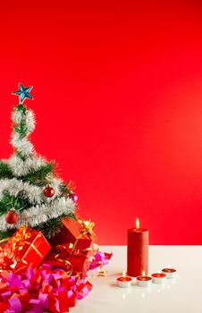 Christmas gifts with candles over red background