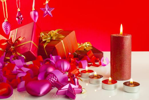 Christmas gifts with candles over red background