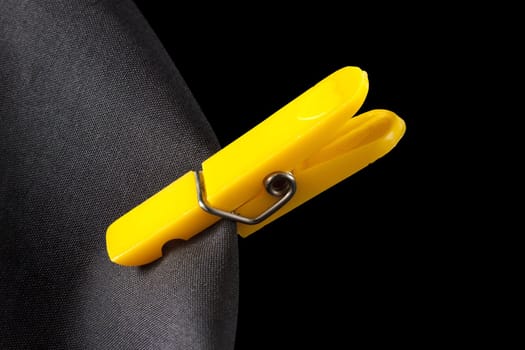 Yellow laundry clip and black cloth on a black background. Clipping path is included