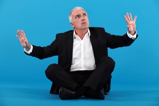 mature businessman gesturing on blue background
