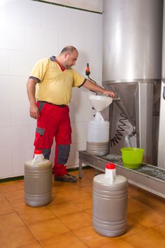 Farmer collecting the freshly pressed oil from his olive crop