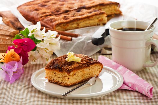 A sheet cake with cinnamon sugar butter and a hot cup of coffee