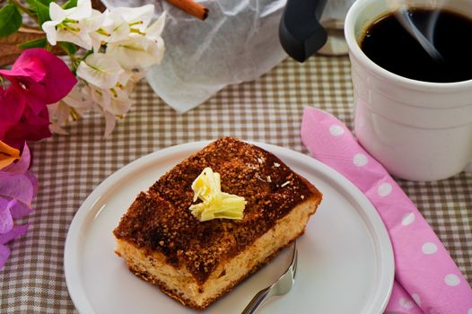 A sheet cake with cinnamon sugar butter and a hot cup of coffee