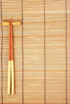 Chopsticks on brown bamboo matting background 