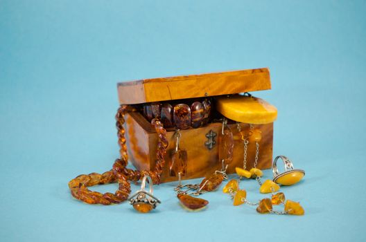amber apparel jewelry ring bracelet in retro wooden box on blue background.