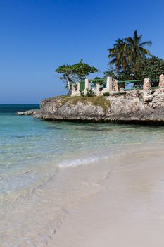 Guardalavaca beach in Cuba with white sand, transparent clean turquoise water and palmtrees against blue sky.