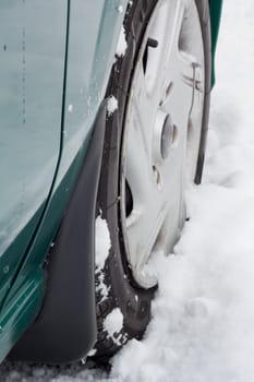Closeup of a car wheel riding on snow.