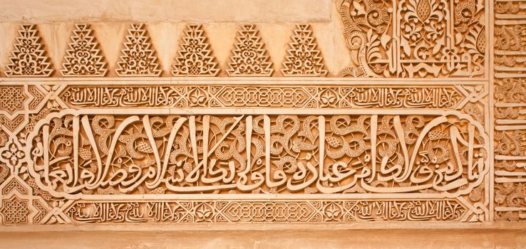 Arabic inscriptions on a wall in the Nasrid Palaces of the Alhambra of Granada, Spain.