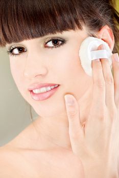 pretty woman applying make up with cosmetic sponge