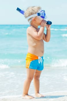 A cute little boy wearing a mask for diving background of the sea
