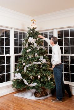 Senior man decorating a Christmas tree in family home