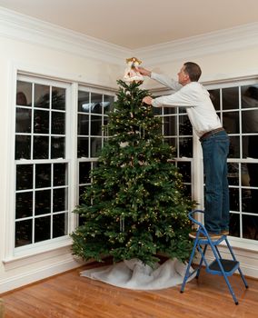 Senior man decorating a Christmas tree in family home