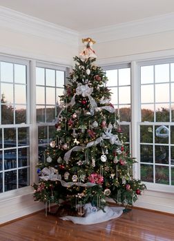 Christmas tree decorated with silver and white ribbons and ornaments in family home