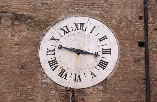 A medieval clock set in a brick wall.  Shot in Siena, Italy.
