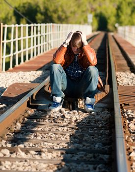 Depressive teenager sitting on a railway track, a concept