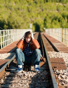 Depressive teenager sitting on a railway track, a concept