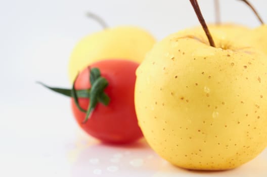 Juicy apples and tomato in drops of water on a white background