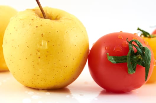 Juicy apples and tomato in drops of water on a white background