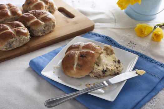 Hot cross bun with butter and butter knife