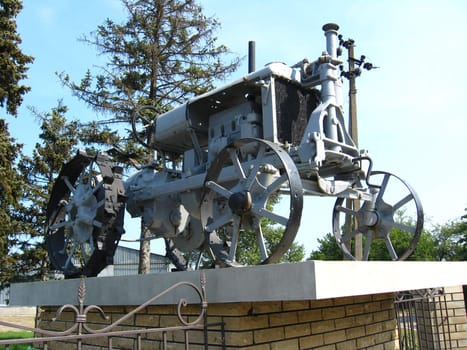 The ancient retro tractor standing on a pedestal