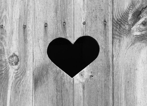 Heart shape look out on wooden door to outhouse.