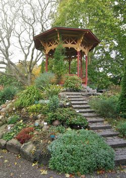 Chinese garden gazebo surrounded by plants and flowers.