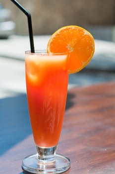 Shot of orange coctail with black straw