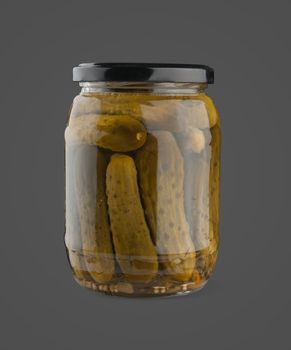 Marinated cucumbers in the glass jar on the dark grey