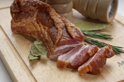 Pieces of bacon with herbs on the wooden board