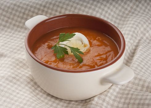 Tomato soup with parsley and boiled egg in the brown and white bowl