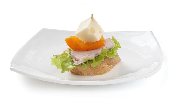Canape with ham, paprika, lettuce and cheese on the white plate