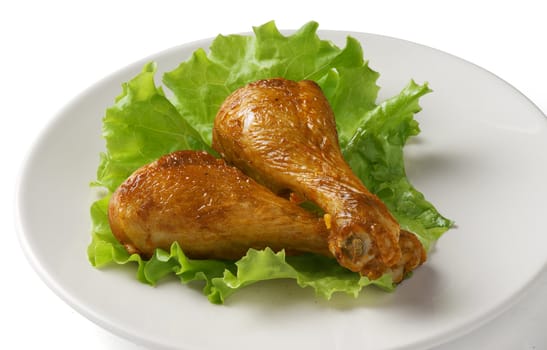 Two chicken legs with lettuce on the plate