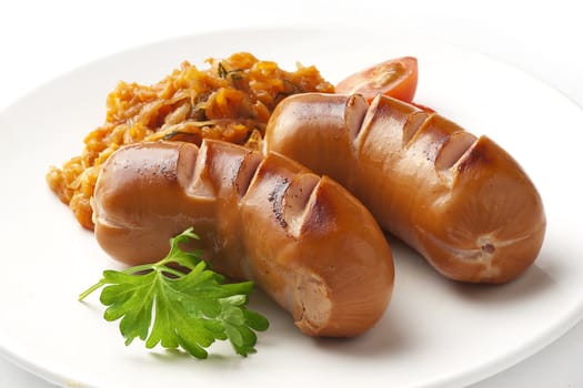 Roasted small sausages with bavarian stewed cabbage and parsley on the plate