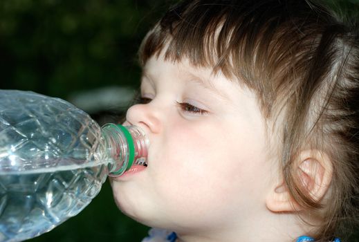 The girl drinking water from a plastic bottle