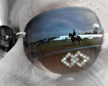 The reflection of a horse and rider in a show jumping arena.