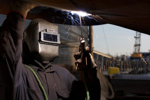 a welder working at shipyard under vessel