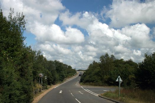 A road in the uk with fluffy clouds.