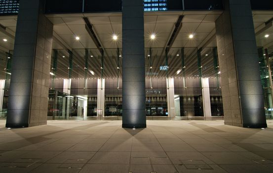 modern architectural background with columns and big glass walls with night illumination in Tokyo, Japan