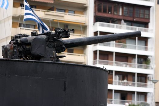 antique fire gun from old navy submarine with houses blur in background  at piraeus athens greece