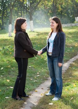 Greeting. Two young beautiful women against park.