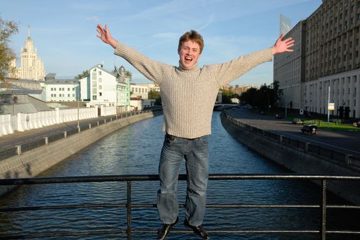 Loud shout. The young man against the river in Moscow.