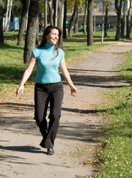 The young beautiful woman walks in autumn park.