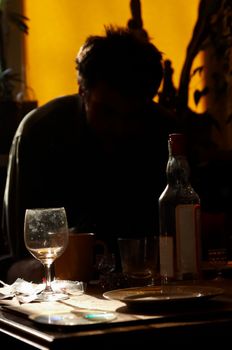 Morning. Man sits at table and smoks cigatrett, near stands  bottle of vodka and glass
