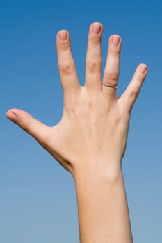 Female hand with a ring on a blue sky