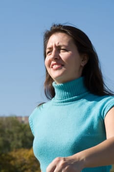 The young beautiful woman walks with blue sky at background